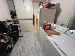 Laundry area featuring cabinets, washer and dryer, and light tile patterned floors