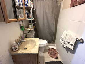 Bathroom featuring tile patterned flooring, walk in shower, toilet, and vanity