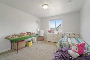 Bedroom featuring light colored carpet and a textured ceiling