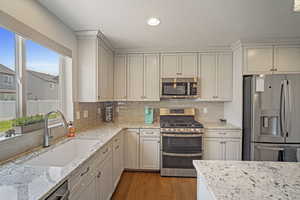 Kitchen with sink, light hardwood / wood-style flooring, appliances with stainless steel finishes, and a wealth of natural light