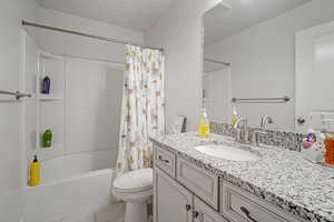 Full bathroom featuring vanity, shower / bath combo with shower curtain, tile patterned flooring, and toilet