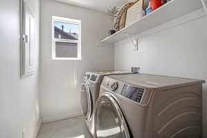 Laundry area with light tile patterned flooring and separate washer and dryer