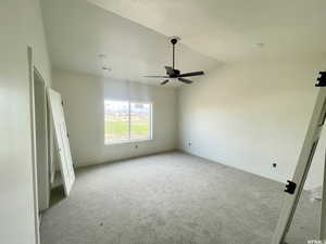 Carpeted spare room featuring lofted ceiling and ceiling fan