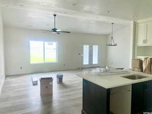 Kitchen with ceiling fan, hanging light fixtures, white cabinets, light hardwood / wood-style flooring, and kitchen peninsula