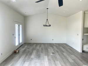 Unfurnished dining area featuring ceiling fan, light hardwood / wood-style flooring, and vaulted ceiling