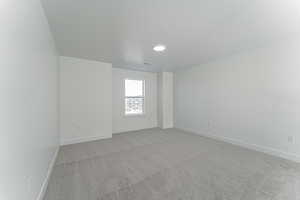 Unfurnished room featuring a textured ceiling and light colored carpet