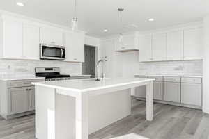 Kitchen with pendant lighting, sink, stainless steel appliances, and a kitchen island with sink