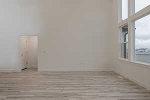 Empty room with a towering ceiling and light hardwood / wood-style flooring