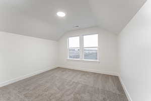 Bonus room featuring carpet and vaulted ceiling