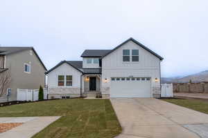 Modern farmhouse style home with a front yard, a mountain view, and a garage