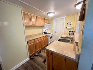 Kitchen featuring sink, a textured ceiling, dark hardwood / wood-style floors, and white appliances