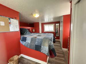 Bedroom with a textured ceiling and dark wood-type flooring