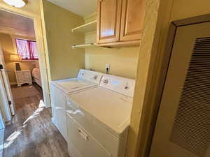 Laundry area featuring washer and dryer, hardwood / wood-style floors, and cabinets