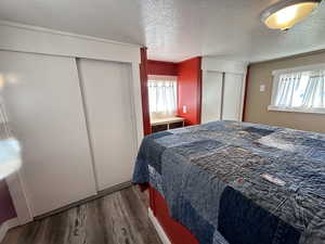 Bedroom with dark hardwood / wood-style flooring and a textured ceiling