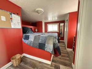 Bedroom with a textured ceiling and dark wood-type flooring