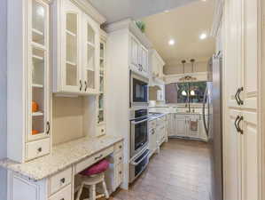 Kitchen featuring pendant lighting, sink, light stone countertops, light hardwood / wood-style floors, and appliances with stainless steel finishes