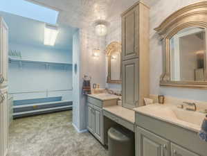 Bathroom with vanity, a textured ceiling, and a skylight