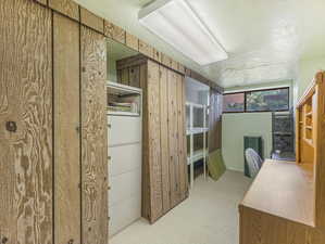 Carpeted office featuring wood walls and a textured ceiling