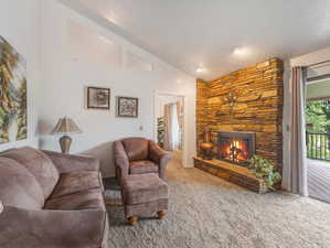 Living room featuring a fireplace, carpet flooring, and lofted ceiling