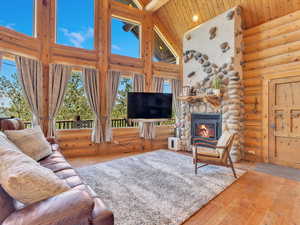 Living room featuring high vaulted ceiling, a fireplace, hardwood / wood-style flooring, and rustic walls