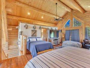 Bedroom featuring vaulted ceiling with beams, hardwood / wood-style floors, log walls, and wood ceiling