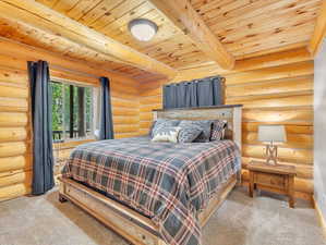 Bedroom with wood ceiling, log walls, beamed ceiling, and light colored carpet