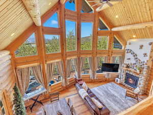 Living room with a fireplace, high vaulted ceiling, beamed ceiling, light hardwood / wood-style floors, and wood ceiling