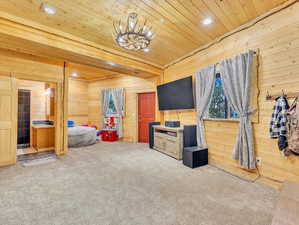 Carpeted living room featuring wood walls and wooden ceiling