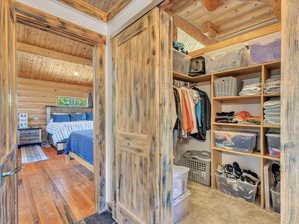 Walk in closet with lofted ceiling with beams and light hardwood / wood-style floors