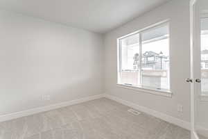 Empty room with carpet floors, baseboards, and visible vents