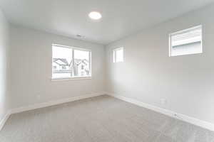 Unfurnished room with light carpet, a textured ceiling, baseboards, and visible vents