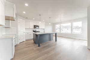 Kitchen featuring light countertops, a sink, a chandelier, appliances with stainless steel finishes, and visible vents