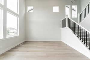 Stairs featuring baseboards, a high ceiling, and wood finished floors
