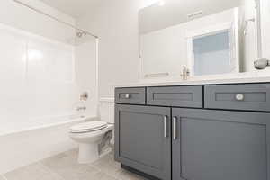 Bathroom featuring visible vents, toilet, tile patterned floors, vanity, and shower / tub combination