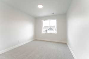 Empty room with baseboards, light colored carpet, and visible vents