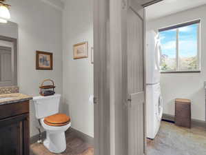 Bathroom featuring stacked washer and dryer, tile patterned floors, toilet, and vanity