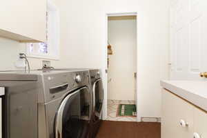 Laundry room with tile patterned floors, washing machine and dryer, and cabinets