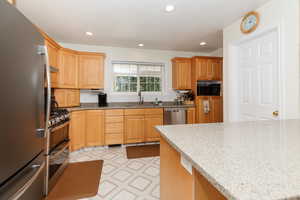 Kitchen featuring sink, light tile patterned floors, light stone counters, and stainless steel appliances