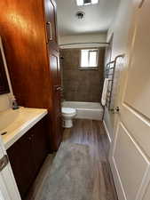 Full bathroom featuring vanity, tiled shower / bath combo, wood-type flooring, and toilet