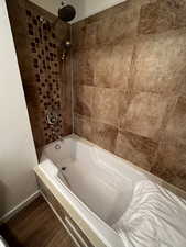 Bathroom with tiled shower / bath combo and hardwood / wood-style floors