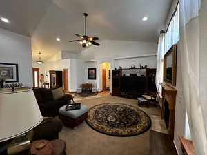 Carpeted living room with high vaulted ceiling and ceiling fan