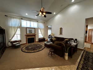 Living room featuring carpet, ceiling fan, and high vaulted ceiling