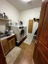 Laundry area featuring sink, washing machine and dryer, cabinets, and tile patterned flooring