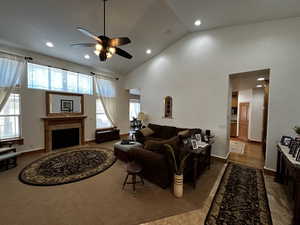 Living room featuring high vaulted ceiling, ceiling fan, and wood-type flooring