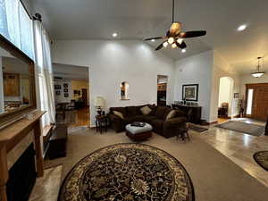 Tiled living room with high vaulted ceiling, ceiling fan, and a fireplace