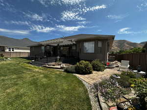 Back of property with a mountain view, a patio area, a lawn, and a pergola