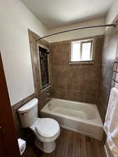 Bathroom with wood-type flooring, toilet, and tiled shower / bath combo