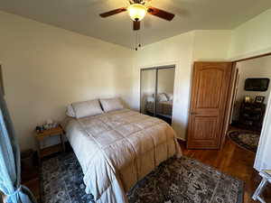 Bedroom featuring ceiling fan, dark hardwood / wood-style floors, and a closet