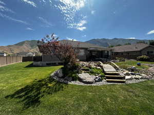 Rear view of property featuring a mountain view and a lawn