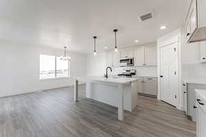 Kitchen featuring white gas stove, an island with sink, wood-type flooring, and sink